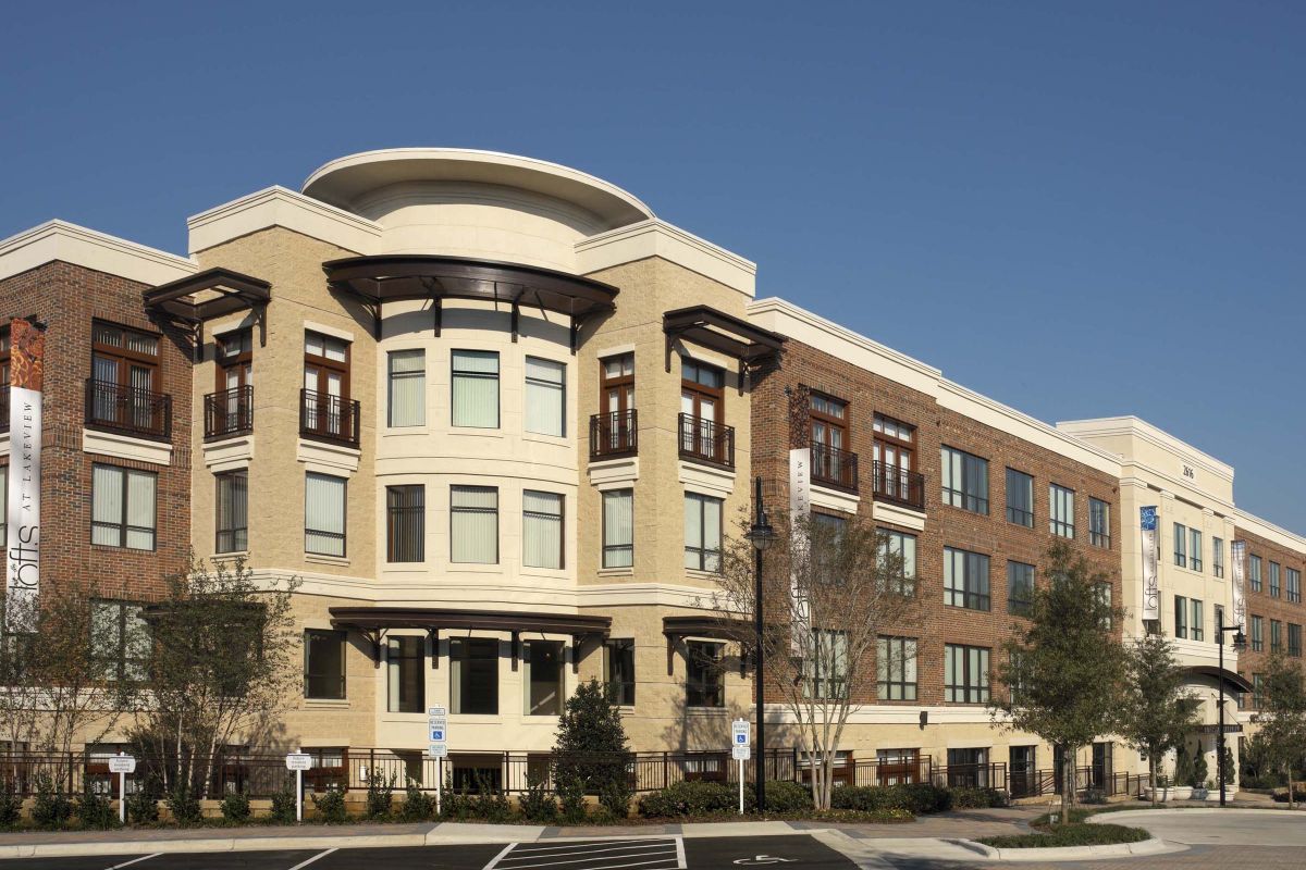 Modern three-story apartment building with brick and cream-colored facade on a sunny day.