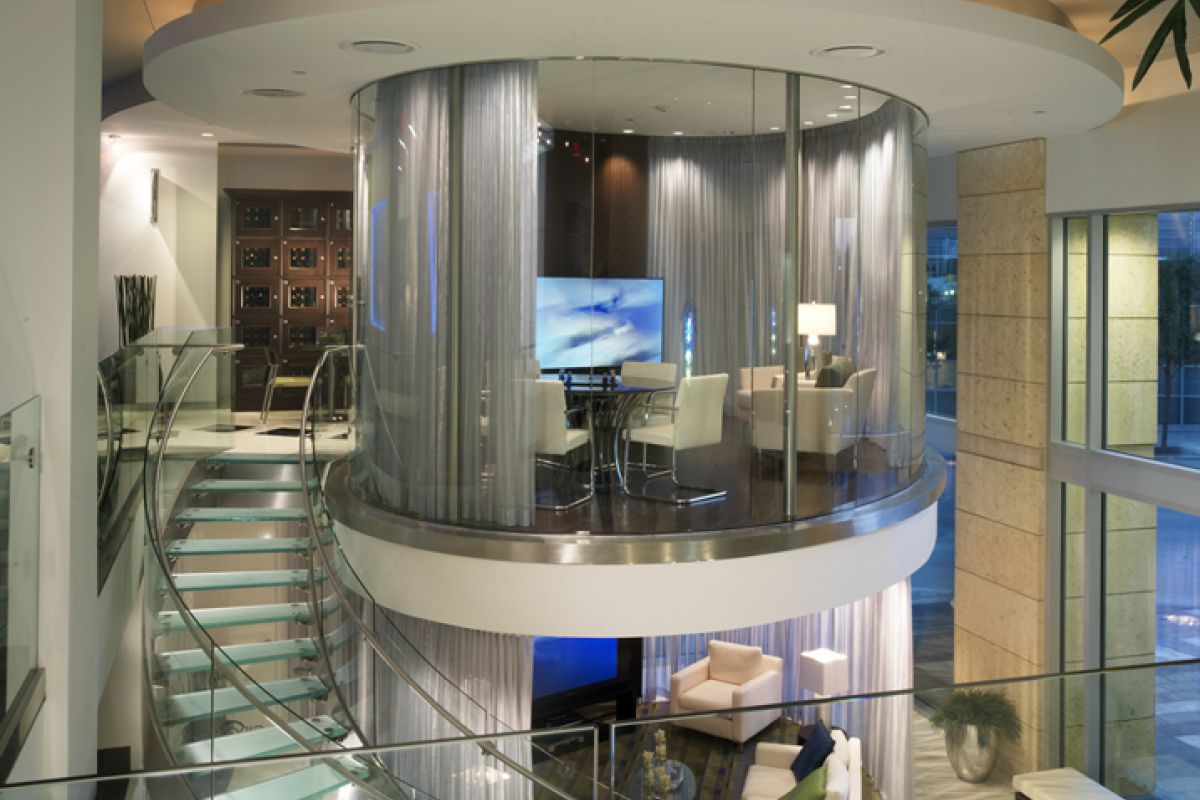 Modern living space with a circular glass-walled room, curved staircase, and contemporary furnishings.