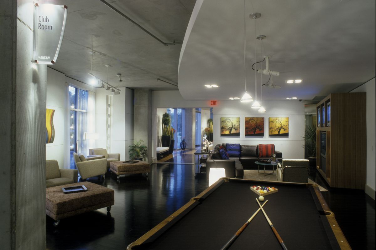 Modern lounge with a pool table, seating area, wall art, and large windows letting in natural light.