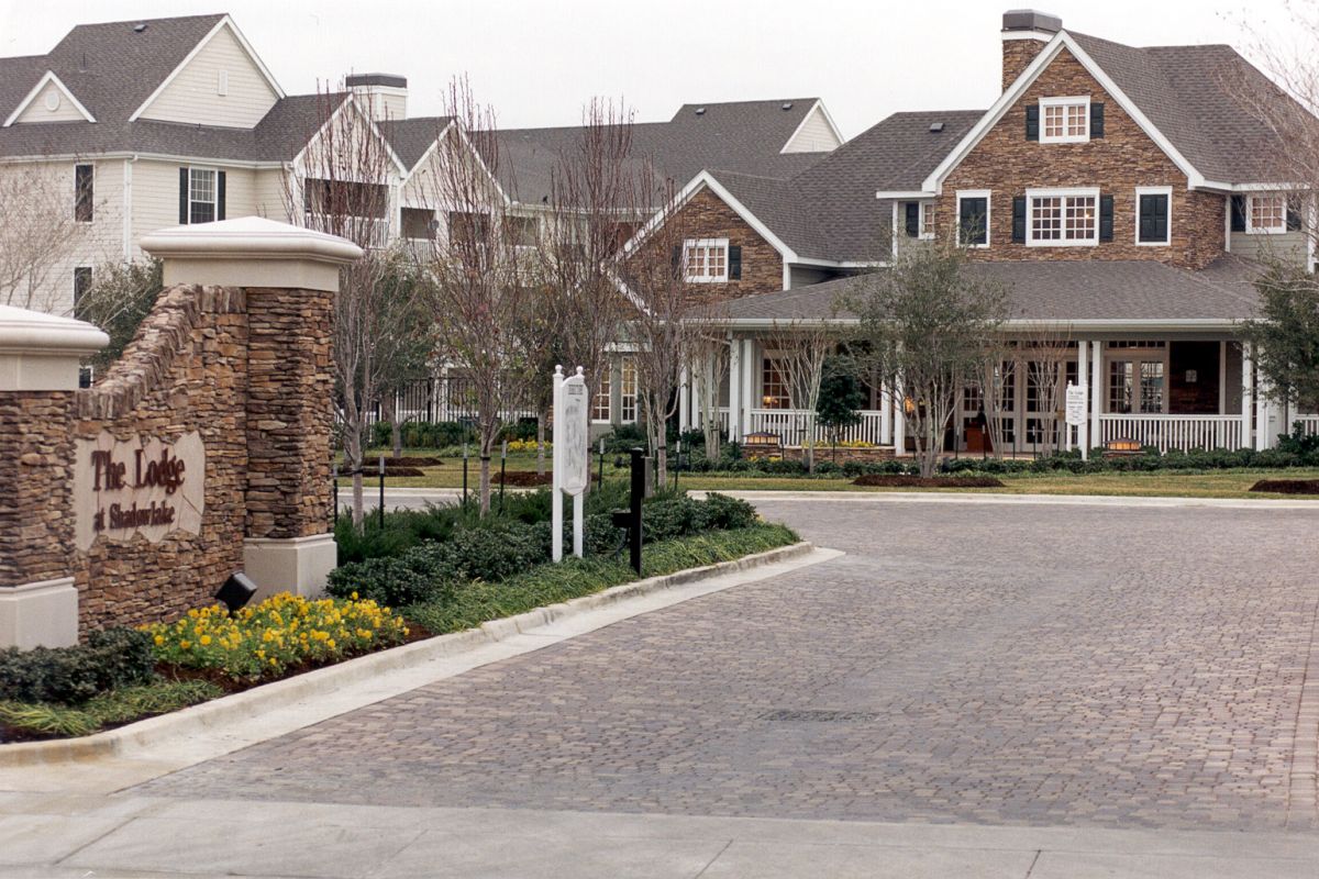 Entrance to The Lodge at Southlake, featuring cobblestone road, landscaped gardens, and large residential buildings.