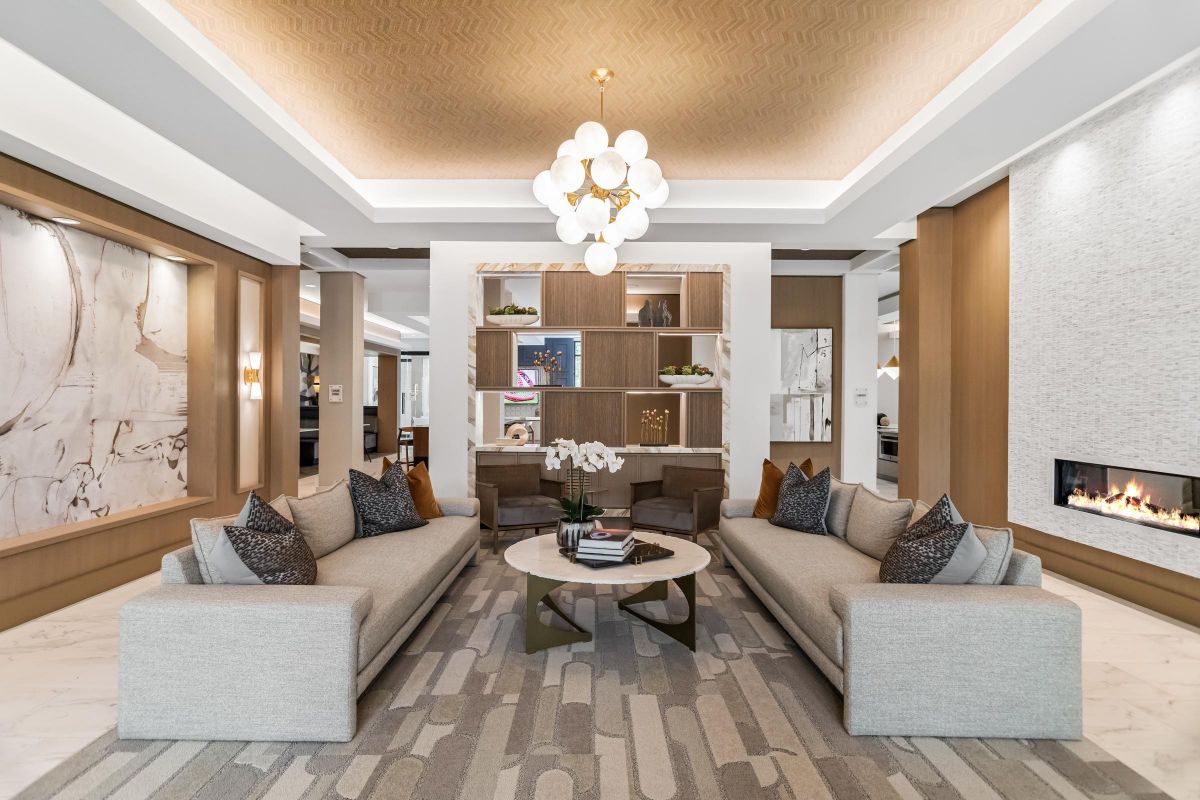 Modern living room with two gray sofas, a round coffee table, chandelier, built-in shelves, and a fireplace.