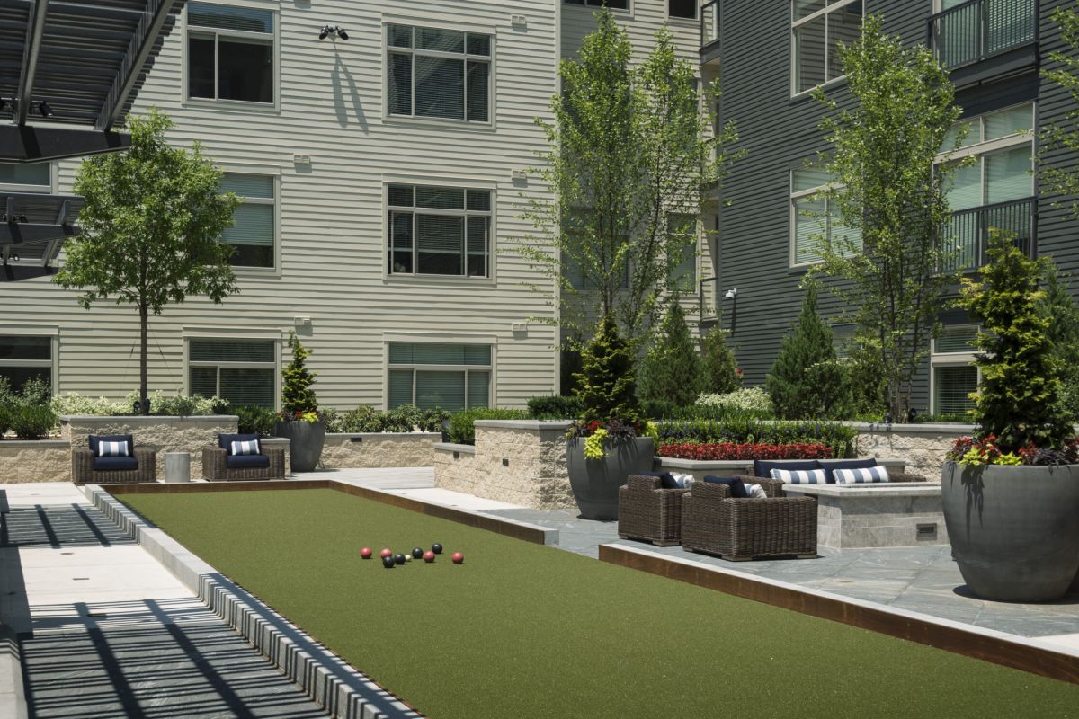 A bocce ball court with seating and plants in a modern apartment courtyard.