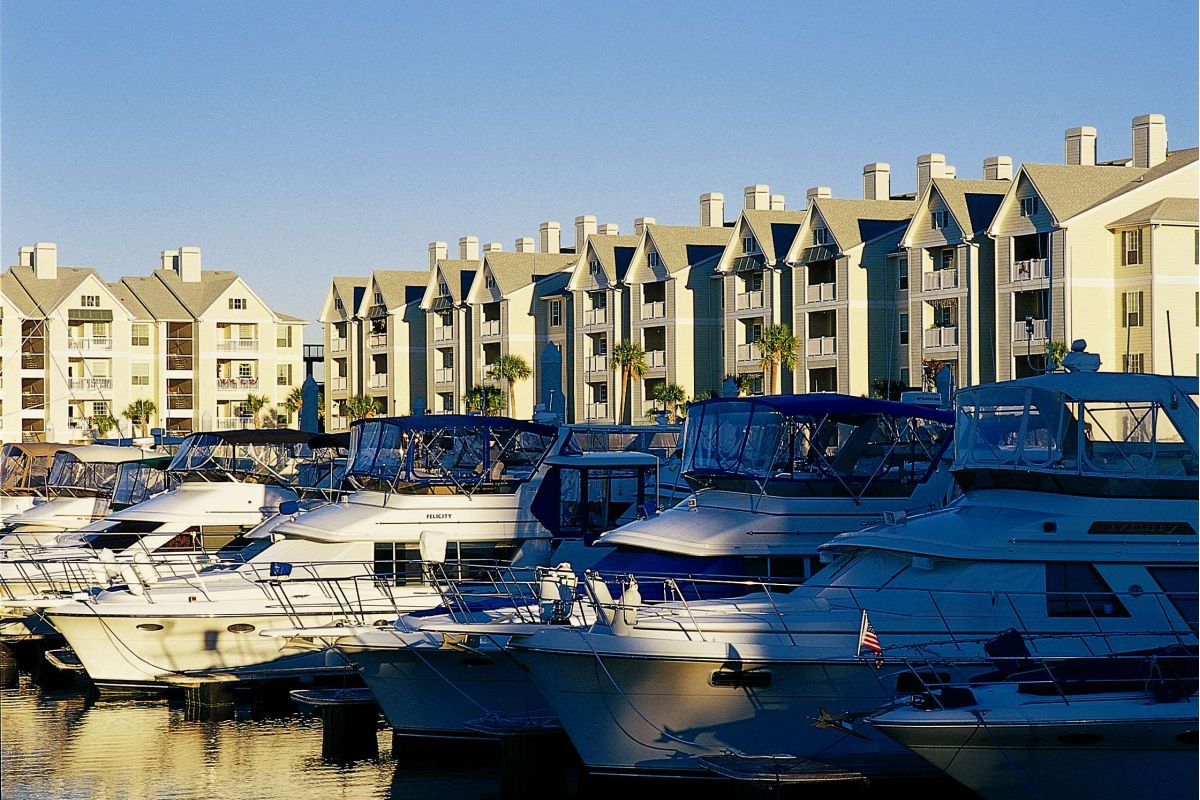 White yachts docked in a marina near Broadwater Galveston condos, set against a clear blue sky.
