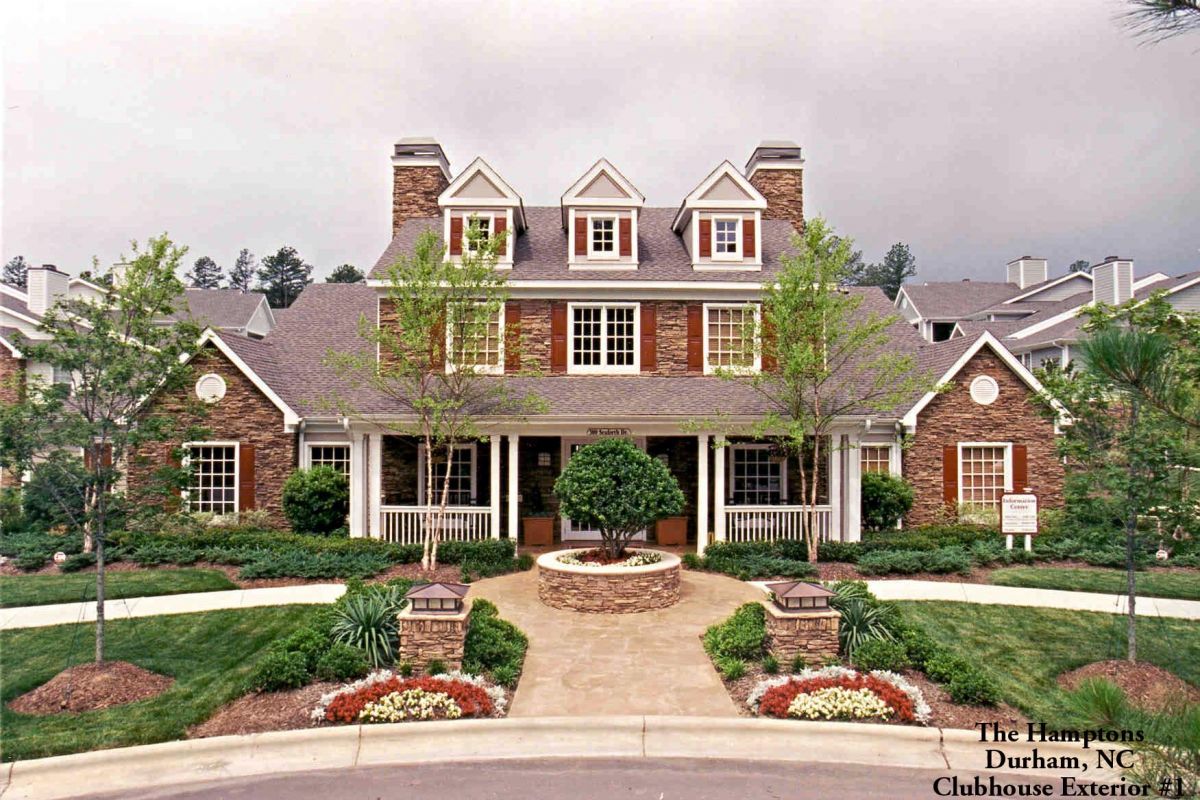 A two-story stone clubhouse with white trim, porch, gardens, and a circular walkway welcomes guests to this Broadwater Galveston hotel.