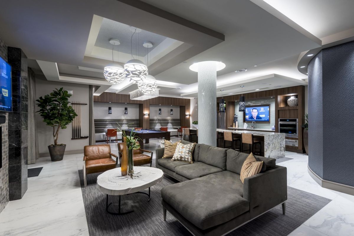Modern lounge with L-shaped sofa, TV, pool table, and contemporary lighting in a sleek, open design space.