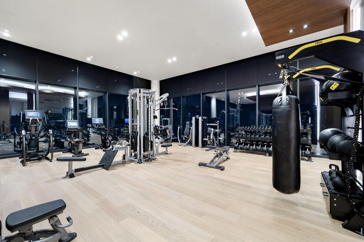 Modern gym with various exercise equipment, including weights, machines, and a punching bag, in a spacious room.