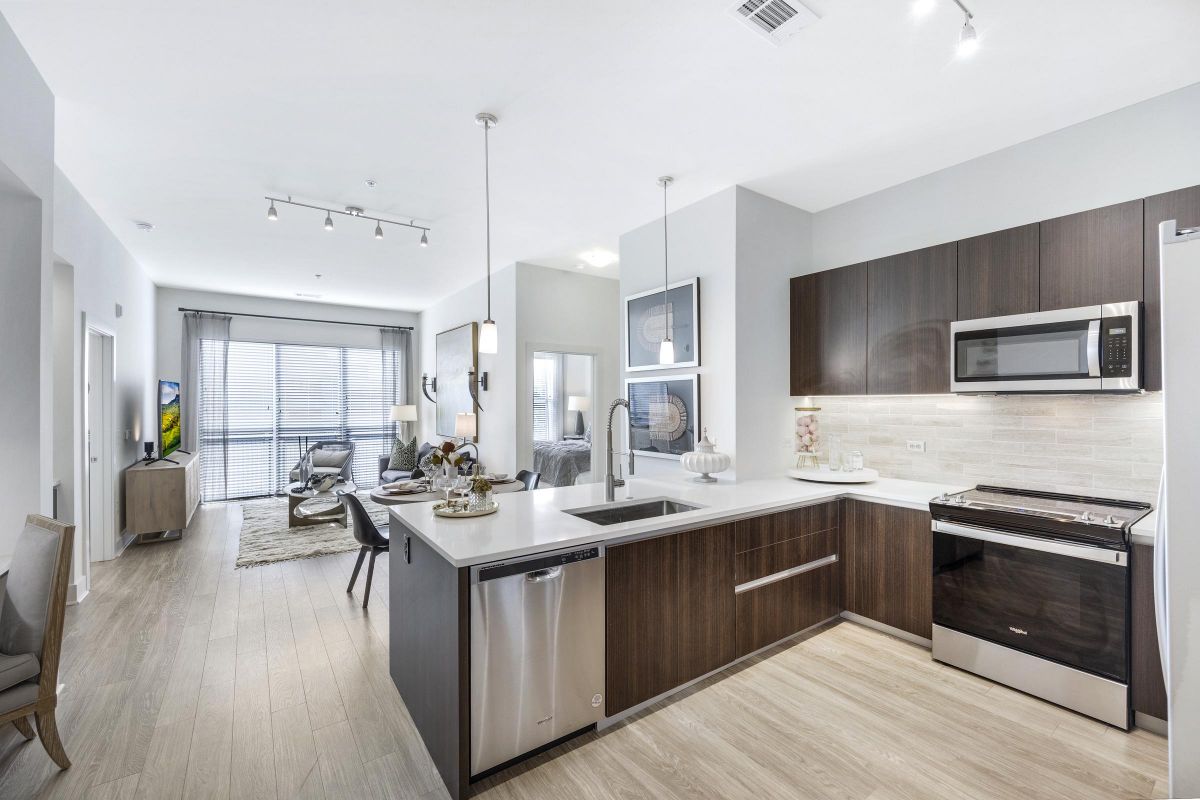 Modern open-concept kitchen and living room with sleek cabinets, island, and cozy seating area. Bright and spacious.