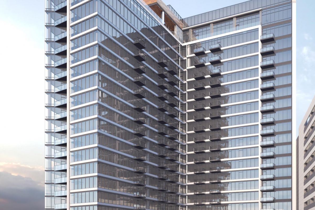 Modern glass high-rise building with balconies and reflective windows against a blue sky background.