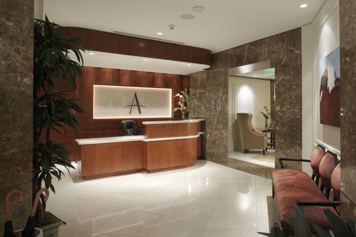 Elegant Ashton Westwood office reception featuring a wooden desk, marble walls, stylish seating, and decor plants.