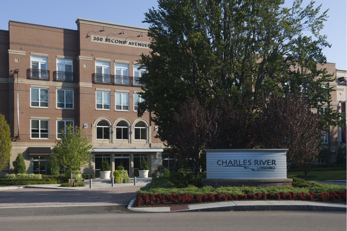 Brick office building with "300 Second Avenue" and "Charles River Lending" signs, surrounded by trees in Charles River Landing.