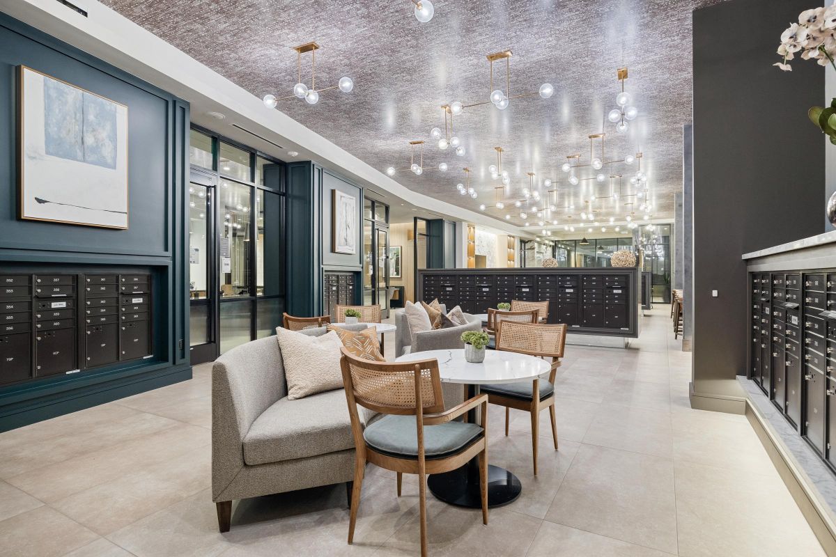 Modern lobby with seating area, contemporary lighting, dark mailboxes, and artwork on walls.