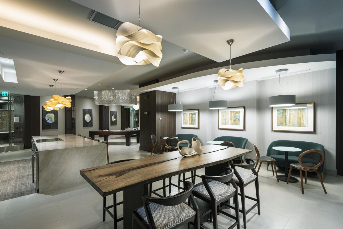 Modern, well-lit lounge with a wooden table, chairs, abstract lights, and framed art on the walls.