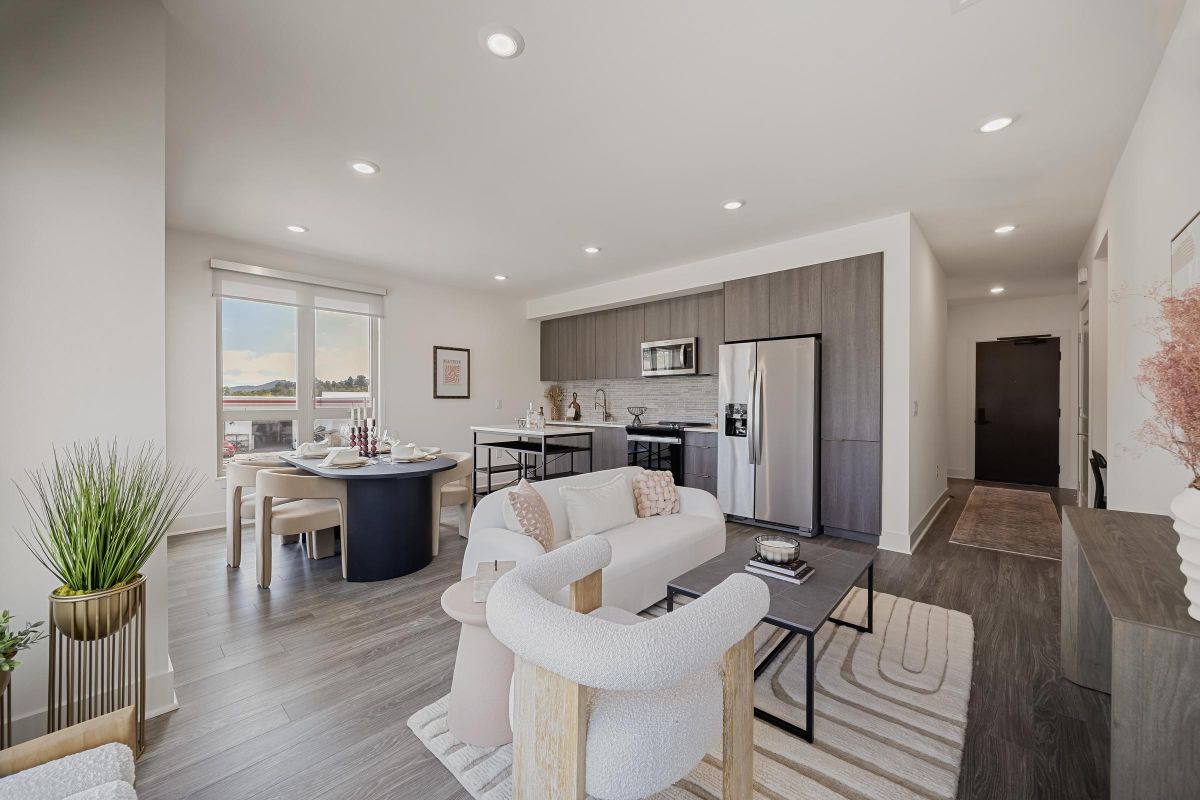 Hanover Laguna Niguel Modern open-plan kitchen and living room with neutral decor, featuring plants and large windows.