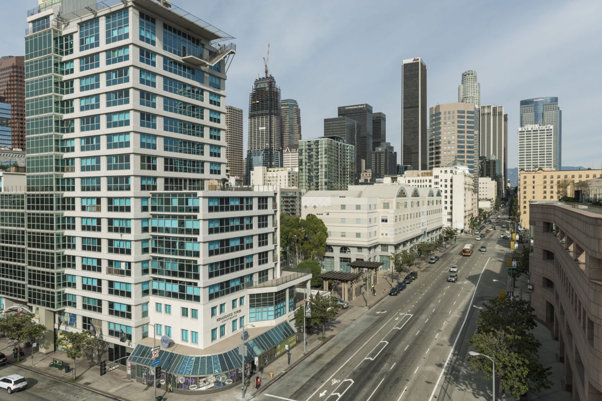 Cityscape with modern buildings and a wide, empty street on a sunny day in downtown Los Angeles.