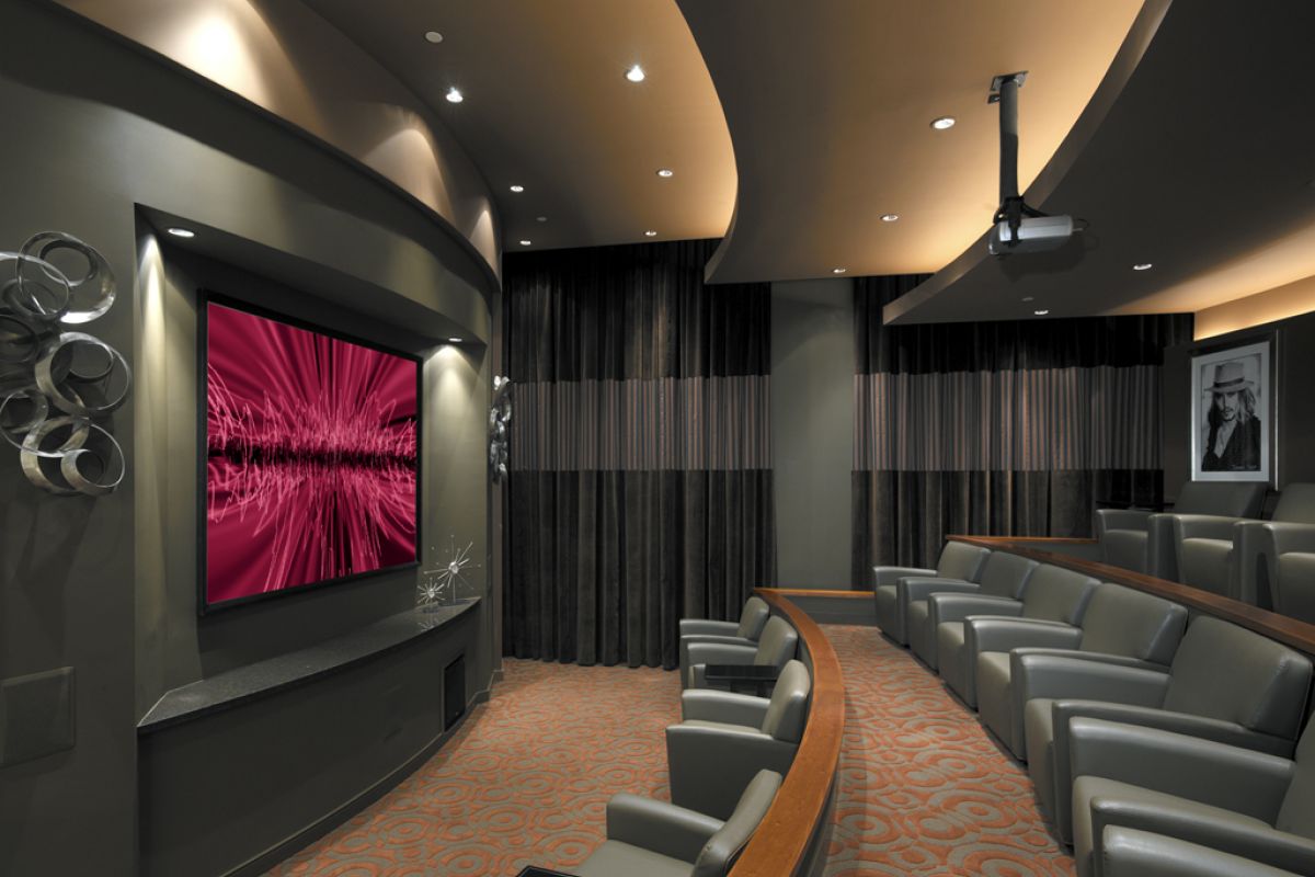Modern home theater with curved rows of gray seats, large screen, and stylish lighting.