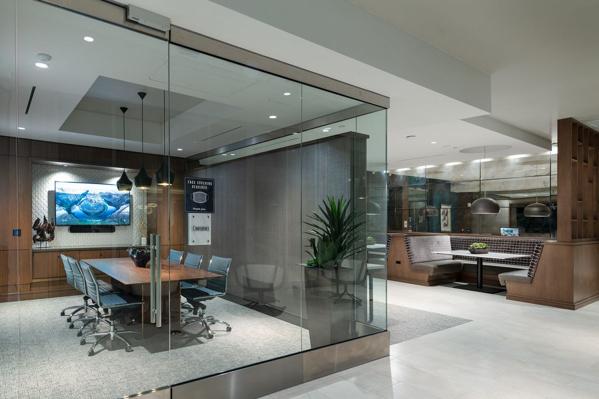 Modern office meeting room with glass walls, a long table, and booth seating, located near Hanover Warner Center apartments.
