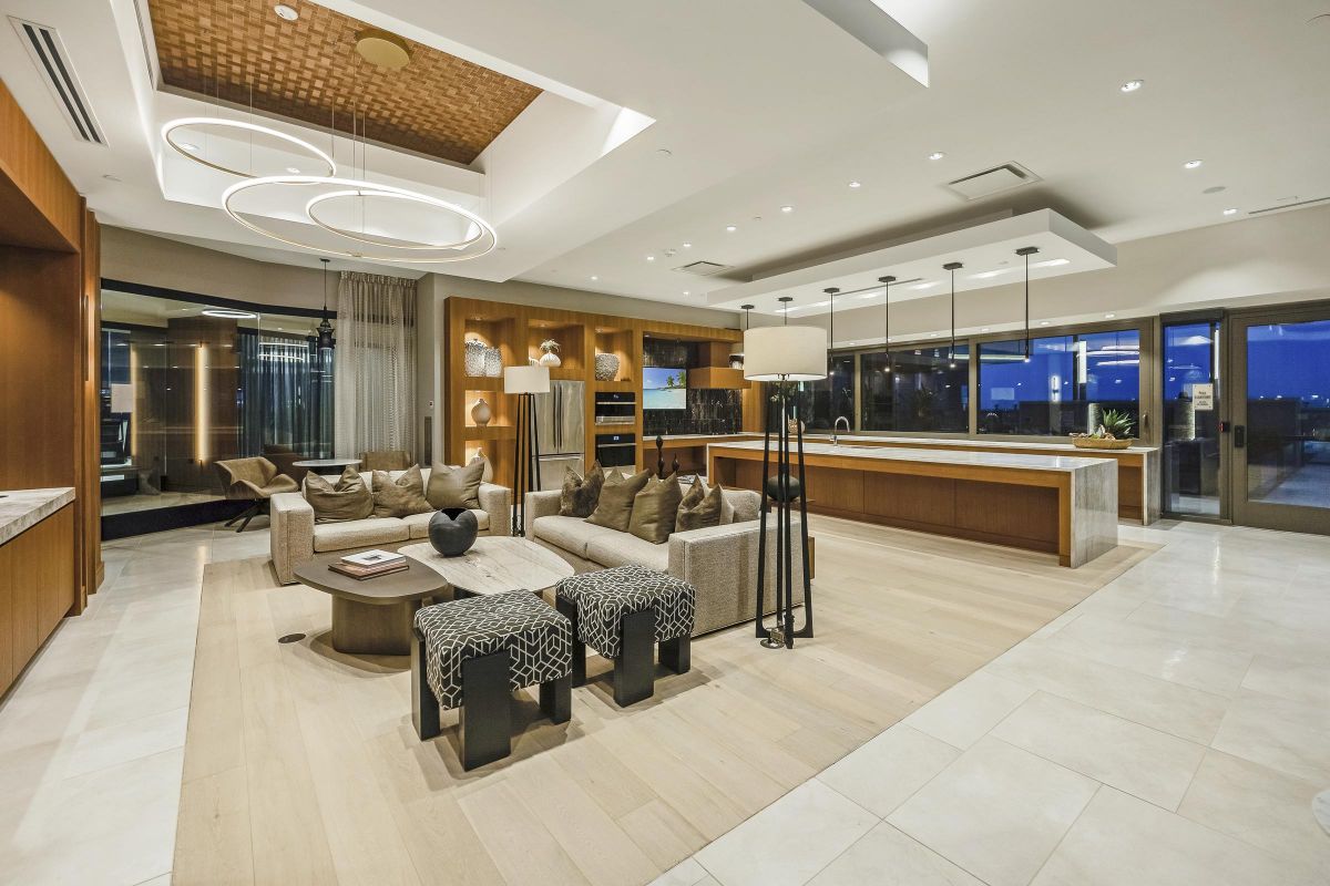 Modern luxury living room with wood accents, stylish sofas, a kitchen island, and circular ceiling lights.