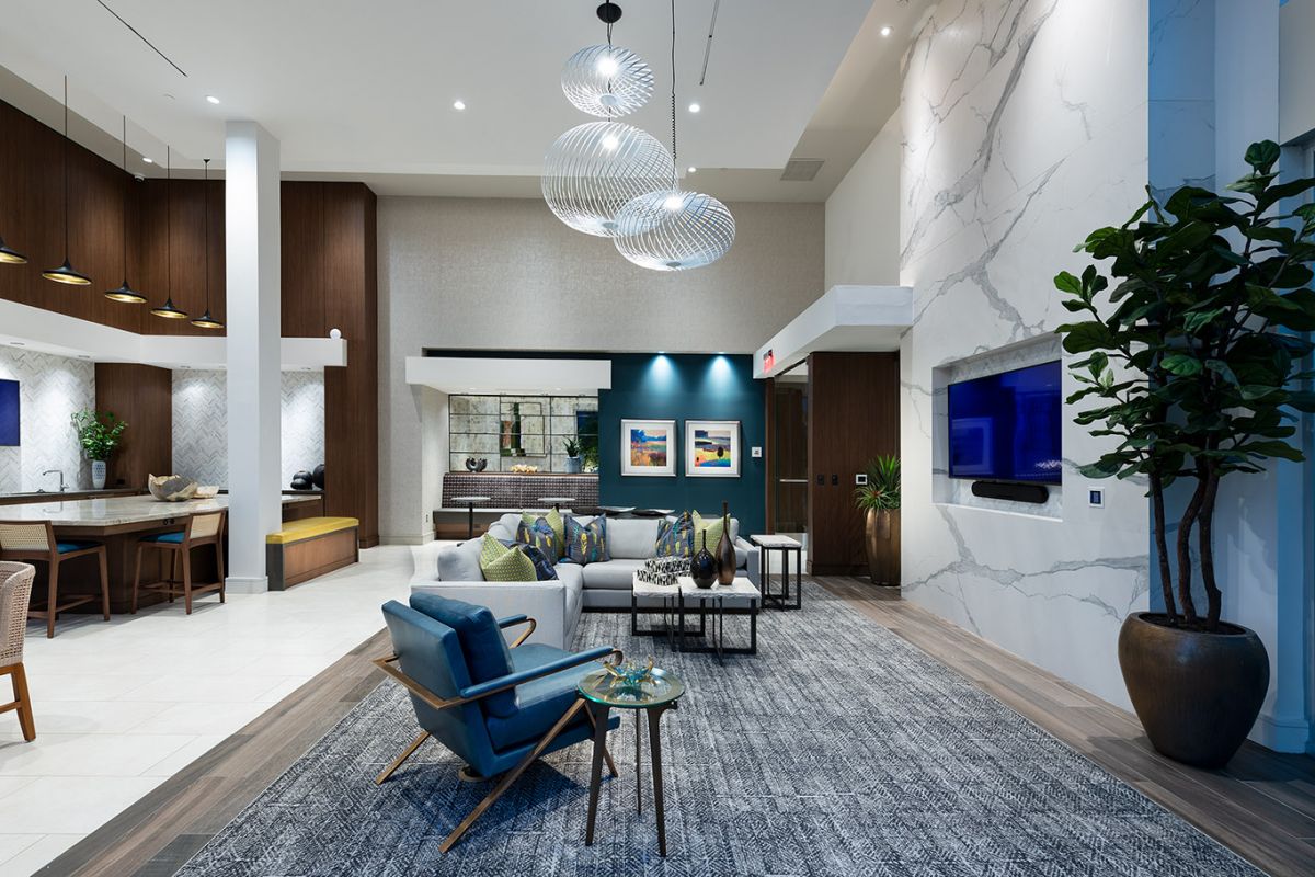 Modern living space at Hanover West LA with blue and gray decor, large TV, kitchen area, and contemporary lighting fixtures.