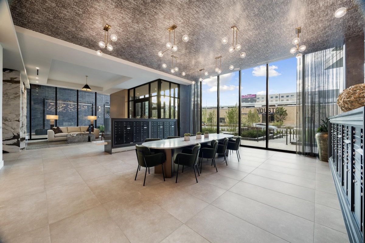 Modern lobby with seating area, large table, stylish lighting, and glass walls overlooking an exterior courtyard.
